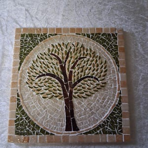 May include: Square mosaic tile with a tree design. The tree has a brown trunk and branches with green and tan leaves. The background is a mosaic of small, light-coloured tiles, framed by a border of tan tiles.