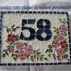 Peut inclure: Une plaque de maison en céramique blanche avec des carreaux de mosaïque bleus et un motif floral. Le numéro 58 est affiché en carreaux de mosaïque bleus. La plaque a une bordure bleue.