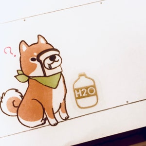 May include: A cartoon illustration of a brown and white dog wearing a green bandana and holding a slice of bread in its mouth. The dog is looking up with a questioning expression. A small bottle with the text "H2O" is to the right of the dog.