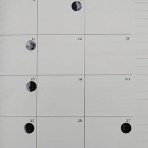 May include: A calendar page featuring a grid with numbered boxes. Several boxes contain circular illustrations of the moon in various phases, ranging from crescent to full. The background is a light, neutral color.