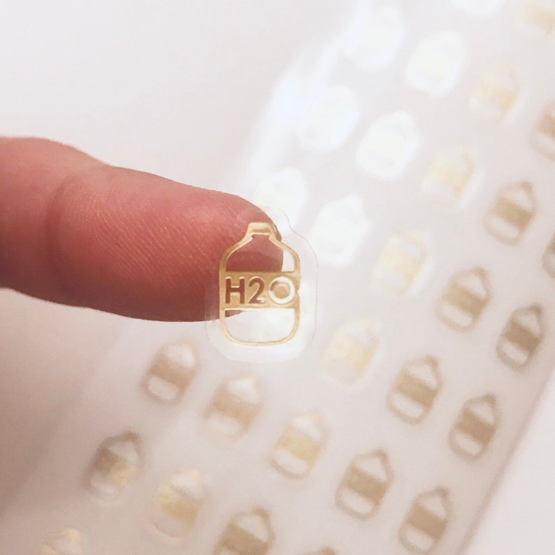 May include: A sheet of clear stickers with gold water bottle icons. Each sticker features a simple outline of a water bottle with the text "H2O" inside.
