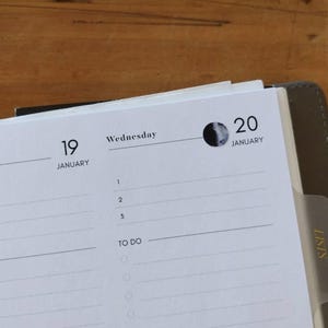 May include: Open planner showing the dates January 19 and 20, Wednesday, with a moon phase graphic. The planner has a section for to-do lists and a tab labeled "LISTS". The pages are white with gray text.