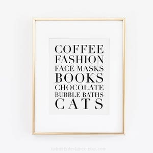 May include: A framed print with a white background and black text that reads "COFFEE FASHION FACE MASKS BOOKS CHOCOLATE BUBBLE BATHS CATS".