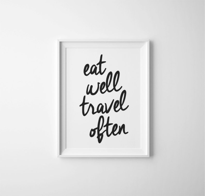 May include: Black and white typography print with the text "eat well travel often" in a white frame.