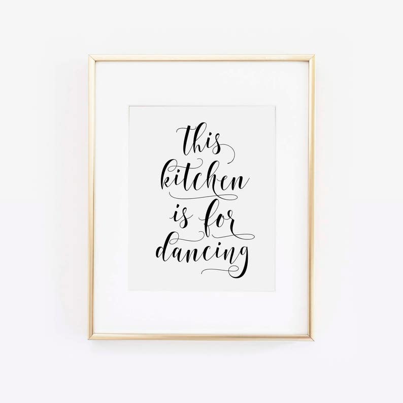 May include: A gold framed print with the text "This kitchen is for dancing" in black cursive font.