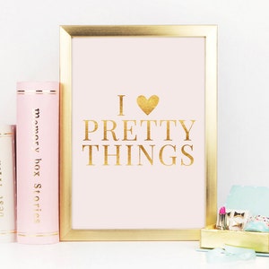 May include: A gold framed print with a pink background and gold lettering that reads "I ♥ PRETTY THINGS".