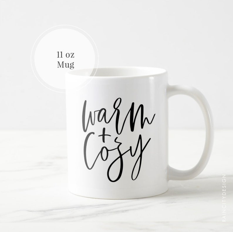 May include: White ceramic mug with black text that reads "warm + cozy". The mug is 11 ounces.
