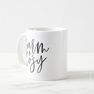 May include: White ceramic mug with black text that reads "Warm + Cozy".