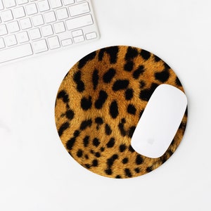 May include: A brown and black leopard print mouse pad with a white wireless mouse on top of it.