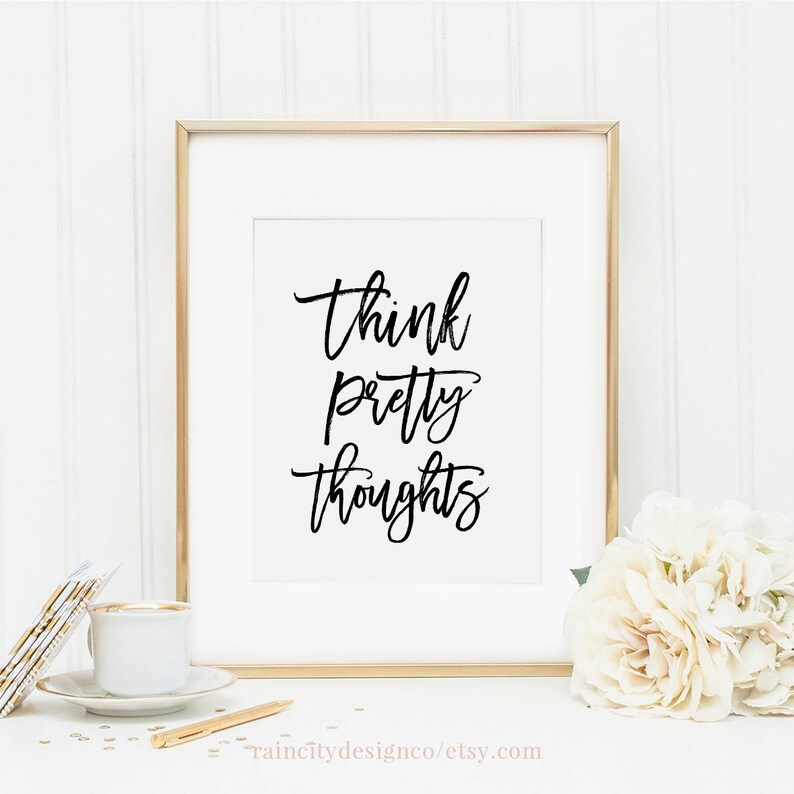May include: A gold framed print with the text "Think pretty thoughts" in black calligraphy on a white background.