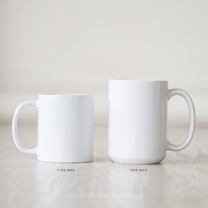 May include: Two white ceramic mugs, one 11 oz and one 15 oz, on a light wood surface. The mugs are blank and ready for personalization.