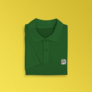 K&ouml;nnte beinhalten: Ein dunkelgr&uuml;nes Poloshirt mit einer kleinen, bunten Grafik auf der rechten Brustseite.