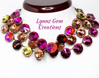 May include: A multi-strand necklace featuring round, faceted crystals in shades of pink, orange, and yellow. The necklace is made with antique brass chain and has a layered, cascading design. Lynn's Gem Creations is printed on the background.