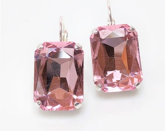 May include: A pair of silver dangle earrings with large, rectangular, pink crystal stones.