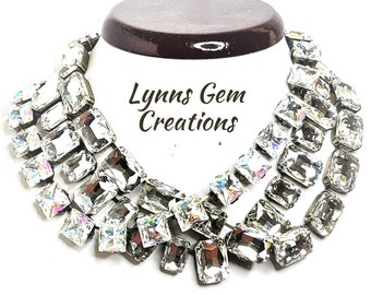 May include: A multi-layered statement necklace featuring large, clear, rectangular crystals. The necklace is displayed on a brown velvet stand. The text "Lynns Gem Creations" is visible in the center of the image.