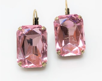 May include: A pair of pink crystal earrings with gold-tone leverback closures. The earrings feature a rectangular, faceted crystal.