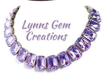 May include: A purple crystal necklace with a rectangular shape. The necklace is made of faceted crystals and has a silver tone finish. The necklace is on a white background. Lynn's Gem Creations.