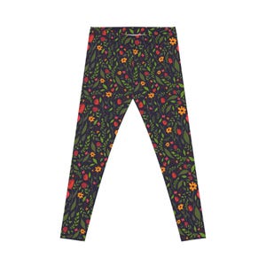 May include: Full-length leggings featuring a dark purple background with a repeating botanical pattern. The print consists of small red tulip-like flowers, bright orange blossoms, and various green leaves and stems scattered across the fabric.
