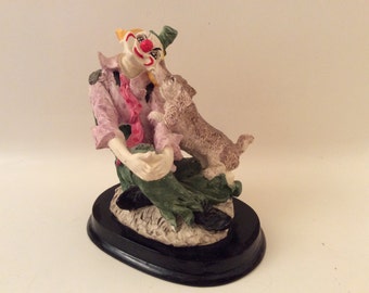 A Cute Figurine of a  Dog Licking a Clown's Face  on a Wood Base.