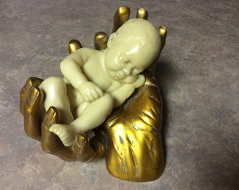 A Lovely Figurine of a Baby Asleep in Gold Hands, Top Collection #2129.