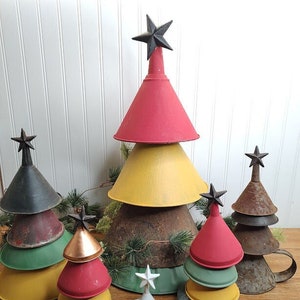 May include: A set of six Christmas trees made from stacked metal funnels. The trees are decorated with red, yellow, green, and white paint. The trees are topped with black star ornaments.