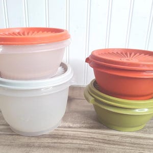 May include: A white ceramic mug with a black handle and the text "But First, Coffee" in a bold, black font. The mug is set against a blurred background, suggesting a cozy setting.