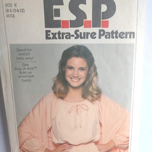 May include: A vintage sewing pattern for a dress, featuring a woman wearing a peach-colored dress with a tie at the neckline. The pattern is for sizes 8, 10, and 12 and is labeled "Simplicity ESP Extra-Sure Pattern 8507".