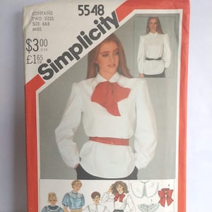 May include: Simplicity sewing pattern number 5548 for a blouse with a bow. The pattern includes two sizes, 6 & 8, for misses. The pattern cover features a white blouse with a red bow, a black belt, and black pants. The pattern also includes instructions for making a variety of collars and bows.
