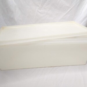 May include: A rectangular, off-white plastic container with a matching lid. The lid is slightly ajar, revealing the interior. The container appears to be made of a translucent material, suggesting it's designed for storage.