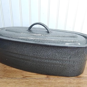 May include: A gray enamel oval roaster with a lid and a handle. The roaster has a speckled gray finish.