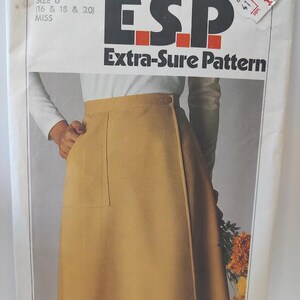 May include: A vintage Simplicity sewing pattern, featuring a tan skirt design. The pattern packet displays the text "ESP Extra-Sure Pattern" and size information for Misses sizes 16, 18, and 20. The image shows a person wearing the skirt.