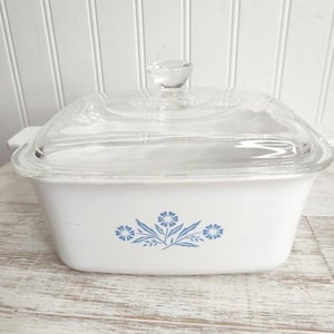 May include: White square baking dish with a glass lid. The dish has a blue floral design with three flowers and leaves.