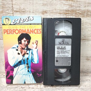 May include: A VHS tape case with a black cassette and a colorful cover featuring Elvis Presley. The cover reads "Elvis: The Lost Performances" and features a photo of Elvis singing into a microphone. The back of the case lists the title, "Elvis: The Lost Performances", and details about the video, including the color, digital video transfer, closed captioned, stereo, and approximate length of 1 hour.