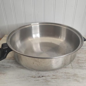 May include: A silver cooking pot with black handles. The pot is empty and has a shiny surface.