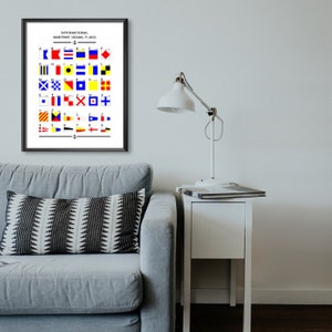 May include: A framed poster with the title "International Maritime Signal Flags" and a chart of 26 flags with their corresponding letters and numbers. The flags are red, yellow, blue, black, and white.