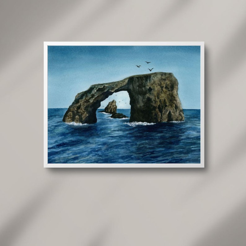 Peut inclure: Une peinture &agrave; l'aquarelle d'une arche rocheuse dans l'oc&eacute;an. L'arche est une formation rocheuse naturelle avec un trou au milieu. L'eau est d'un bleu profond et quelques oiseaux volent dans le ciel.