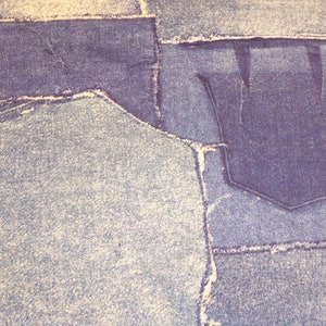 May include: A close-up of a denim fabric with a patchwork design. The fabric is made up of different shades of blue and has a distressed look.