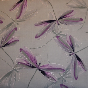 Può includere: Un tessuto grigio chiaro con un motivo ripetitivo di libellule viola e verdi. Le libellule sono contornate da piccoli punti bianchi.