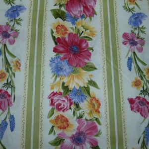 Pode incluir: Um tecido branco com listras verdes e um padrão floral. As flores são rosa, azul, amarelo e branco. O tecido tem um toque vintage.