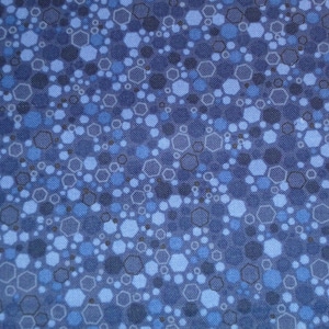 Op de afbeelding: Een blauwe stof met een herhalend patroon van kleine en grote zeshoeken in tinten blauw.
