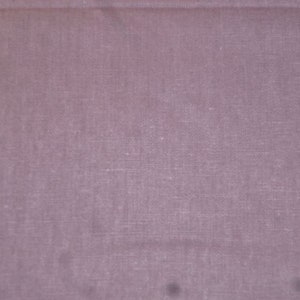 Peut inclure: Un gros plan sur un tissu uni de couleur mauve clair avec une texture tissée subtile.