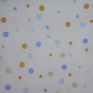 Op de afbeelding: Witte stof met een verspreid patroon van blauwe, gouden en groene stippen.