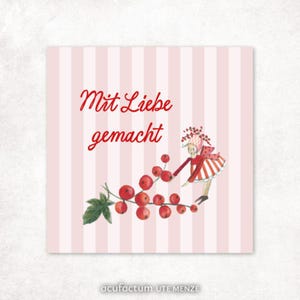 Op de afbeelding: Vierkante kaart met een roze en witte gestreepte achtergrond. De tekst "Mit Liebe gemacht" staat in rode letters. Waterverfillustratie van een persoon in rood en wit die een tros rode bessen vasthoudt. De naam van de kunstenaar staat onderaan.