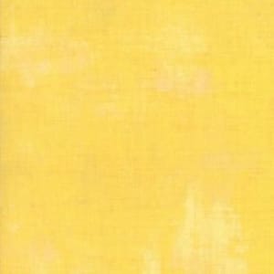 Może przedstawiać: Jednolity żółty materiał z subtelnym, fakturowanym wzorem. Materiał ma lekko wyblakły wygląd, co nadaje mu vintage'owy charakter.