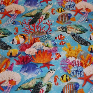 May include: A colourful fabric with a repeating pattern of sea life, including sea turtles, fish, coral, and starfish. The background is a light blue.