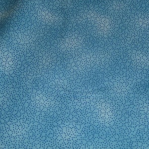 Może przedstawiać: Niebieski materiał z białym i niebieskim wzorem w kropki. Materiał ma subtelną fakturę i miękki, jasnoniebieski kolor.