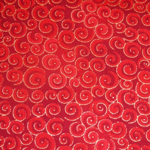 Op de afbeelding: Rode stof met een herhalend patroon van gouden swirls.