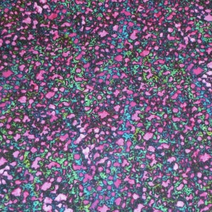 Può includere: Un tessuto con un motivo astratto rosa, verde e blu. Il motivo è composto da piccole forme irregolari che ricordano punti o macchie.