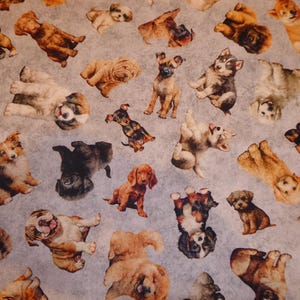Puede incluir: Un patrón de tela repetido que presenta varias razas de perros en diferentes poses. Los perros son de color marrón, beige, negro y blanco, sobre un fondo gris claro. El patrón incluye cachorros y perros adultos.