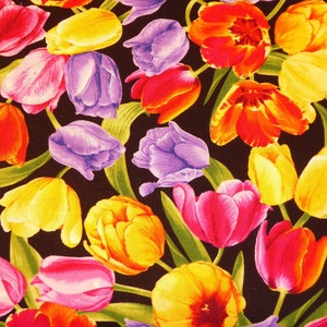 Op de afbeelding: Een kleurrijke stof met een herhalend patroon van tulpen in verschillende tinten rood, roze, geel, paars en blauw. De tulpen zijn willekeurig gerangschikt op een zwarte achtergrond.